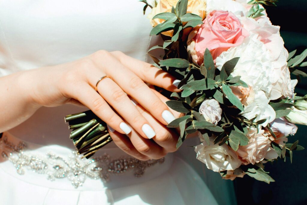 Close-up of a bride holding a beautiful wedding bouquet with an elegant ring on her hand.